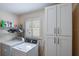 Bright laundry room features a washer and dryer, storage cabinets, and a window with plantation shutters at 704 Tangerine Ct, Winter Garden, FL 34787