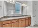 Double vanity bathroom featuring wood cabinets, gray countertops, updated faucets, and dual mirrors at 8518 Nemours Pkwy, Orlando, FL 32827