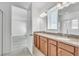 Bathroom with double vanity, wood cabinets, gray countertops, dual mirrors, and a view of the bedroom at 8518 Nemours Pkwy, Orlando, FL 32827
