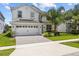 Two-story home featuring a manicured lawn, beautiful landscaping, and an attached two-car garage at 8822 Interlocking Ct, Davenport, FL 33896