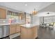 Open kitchen area with light wood cabinets, hardwood floors, stainless steel appliances, and an island at 10930 Buckwater Ct, Orlando, FL 32817