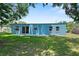 A spacious backyard featuring a blue exterior, a sliding glass door, a patio, and lush green grass at 11520 Churchill St, Orlando, FL 32817