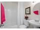 Cozy bathroom featuring a pedestal sink, floral art, and a tub-shower combo with white tile at 11520 Churchill St, Orlando, FL 32817