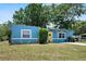 Attractive blue home with a yellow door, lush greenery, and a well-kept lawn, creating a welcoming curb appeal at 11520 Churchill St, Orlando, FL 32817