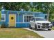 Charming blue home with a bright yellow front door, complemented by lush landscaping and ample parking at 11520 Churchill St, Orlando, FL 32817