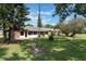 Large, grassy backyard featuring mature trees and a brick patio, offering a serene outdoor space at 1230 Americana Pl, Orlando, FL 32807