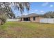 Spacious backyard with a manicured lawn, a screened-in patio, and a white fence at 1913 Lazy Oaks Loop, St Cloud, FL 34771