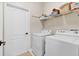 Functional laundry room featuring a white washer and dryer and a storage shelf at 1913 Lazy Oaks Loop, St Cloud, FL 34771