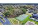 Aerial shot of a tennis court in a neighborhood with sidewalks and mature trees adding to the surroundings at 1913 Lazy Oaks Loop, St Cloud, FL 34771