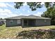 Exterior view of the rear of the home with a patio and partially grassy backyard and a few trees at 1947 Vienna Ave, Deltona, FL 32725
