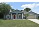 Charming blue home featuring a two-car garage, well-manicured lawn, and covered front entry way at 1947 Vienna Ave, Deltona, FL 32725