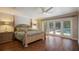 Light-filled bedroom featuring a four-poster bed, hardwood floors, and French doors leading to a pool at 2009 Woody Dr, Windermere, FL 34786