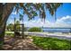 Scenic lake view with benches, a walking path, and an old tree with hanging Spanish moss at 2009 Woody Dr, Windermere, FL 34786