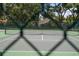 A tennis court with a green surface surrounded by a dark green fence and tall trees at 2009 Woody Dr, Windermere, FL 34786