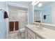 Well-lit bathroom featuring a shower, sink, and mirror against light blue walls at 2562 Sheffield Dr, Deltona, FL 32738