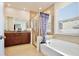 Bright bathroom with double vanity, large mirror, soaking tub, and glass enclosed shower at 2598 Trielle Ave, Kissimmee, FL 34741