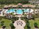 Aerial view of a resort-style pool with palm trees, lounge chairs, and a fire pit area in a Primary-planned community at 2598 Trielle Ave, Kissimmee, FL 34741