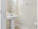 A pristine half-bathroom featuring a pedestal sink, a decorative mirror, and neutral wall and floor tiles at 3018 Bargate St, Orlando, FL 32824