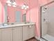 Pink bathroom featuring double vanity, marble countertops, a glass-enclosed shower, and decorative lighting at 3020 Parrot Head Pl, Kissimmee, FL 34747