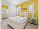 Bright bedroom features a comfortable bed, yellow accents, and a glimpse of the connecting bathroom, creating a serene space at 3020 Parrot Head Pl, Kissimmee, FL 34747