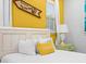 Bedroom showing bed with bright yellow accents, a bedside table, and a charming decor sign for a vibrant, cozy atmosphere at 3020 Parrot Head Pl, Kissimmee, FL 34747