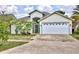 Charming single-story home with a white garage door, green trimmed entrance, and a beautiful flowering shrub in the front yard at 3029 Bransbury Ct, Kissimmee, FL 34747