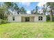 A home's backyard featuring green grass, some trees, a covered patio, and sliding glass doors into the home at 30369 Apricot Ave, Eustis, FL 32736