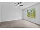 Spacious bedroom with plush carpet, ceiling fan, and a large window showcasing a private backyard at 30369 Apricot Ave, Eustis, FL 32736