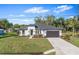Beautifully landscaped single-story home featuring a dark gray roof, black garage door, and well-maintained lawn at 30369 Apricot Ave, Eustis, FL 32736