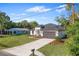 Well-manicured lawn and landscaping leading up to a modern white home with a gray roof and dark garage door at 30369 Apricot Ave, Eustis, FL 32736