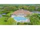 Aerial view of community clubhouse and pool with tanning deck, manicured landscaping, and adjacent parking at 3128 Stonehurst Cir, Kissimmee, FL 34741