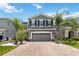Beautiful two story home with a well manicured lawn and a brick driveway with palm trees flanking the home at 3883 Crawley Down Loop, Sanford, FL 32773