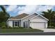 Charming one-story home featuring a well-maintained lawn, two car garage, and light gray stucco exterior at 415 Puma Loop, Groveland, FL 34736