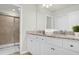 Bathroom boasts double sinks, granite countertop, white cabinets, and a shower with a glass door at 4310 Lana Ave, Davenport, FL 33897