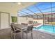 A covered patio has a table, chairs, and lounge chairs by the pool with screened enclosure at 4310 Lana Ave, Davenport, FL 33897
