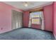 Cozy bedroom features blue carpet, pink walls, closet, and window with curtains at 485 Whittingham Pl, Lake Mary, FL 32746