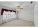 Large carpeted bedroom with ceiling fan and big bright window with curtains at 4895 Cr 134B, Wildwood, FL 34785