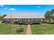 Charming brick home featuring a metal roof, well-manicured lawn, and inviting porch seating at 4895 Cr 134B, Wildwood, FL 34785