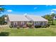 Well-manicured lawn and a charming brick home with a metal roof and inviting covered porch at 4895 Cr 134B, Wildwood, FL 34785