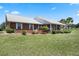 Well-maintained brick home with manicured landscaping and a covered front porch featuring swing seating at 4895 Cr 134B, Wildwood, FL 34785
