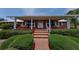Charming brick home with inviting front porch, white columns, swings, and manicured landscaping at 4895 Cr 134B, Wildwood, FL 34785