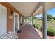 Inviting brick front porch with swing and elegant white columns, perfect for relaxing and enjoying the outdoor view at 4895 Cr 134B, Wildwood, FL 34785