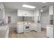 Well-lit kitchen featuring white cabinetry, modern appliances, and wood flooring at 4895 Cr 134B, Wildwood, FL 34785