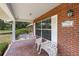 Inviting porch with brick flooring, cozy swing, and decorative seating next to a brick wall at 4895 Cr 134B, Wildwood, FL 34785