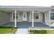 Covered porch with white pillars, grey painted floor and white door with decorative window at 5160 Wood Ridge Ct, Ocoee, FL 34761