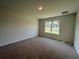 A bright bedroom features neutral walls, brown carpeting, and a window letting in natural light at 5350 Pine Lilly Dr, St Cloud, FL 34771