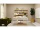 Bright home office with floating shelves, a large plant, and a comfortable seating area at 773 Tundra Loop, Groveland, FL 34736