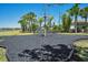 Playground with black mulch and a pyramid climbing structure, surrounded by green grass and palm trees at 8256 Bayview Crossing Dr, Winter Garden, FL 34787
