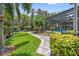 An inviting brick-paved walkway leads through lush landscaping to the screened-in pool at 8612 Summerville Pl, Orlando, FL 32819