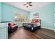 Cozy bedroom featuring plantation shutters, wood-look floors, accent chair, and a comfortable bed at 8612 Summerville Pl, Orlando, FL 32819